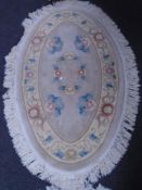 A Chinese floral embossed oval fringed rug