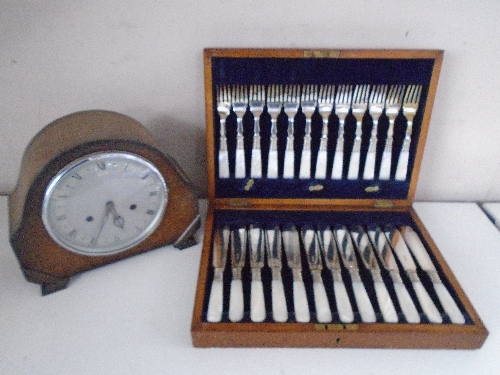 An Edwardian oak mantel clock together with an oak canteen of fish cutlery