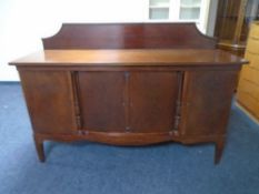 An early 20th century mahogany four door sideboard on raised legs.