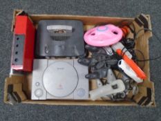 A box containing a Sony PlayStation, Nintendo 64, controllers, a Wii drive etc.