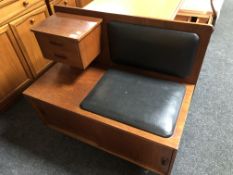 A mid-20th century teak telephone table with black vinyl seat.