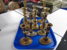 A tray containing five pairs of antique candlesticks.