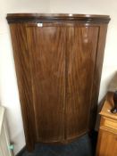 An antique mahogany bow fronted double door corner cabinet.