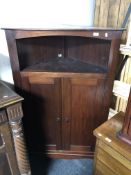 An early 20th century mahogany double door corner cabinet on raised legs.