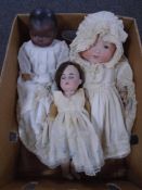 A box containing three 20th century porcelain dolls.