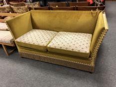 A 20th century drop end settee upholstered in gold fabric.