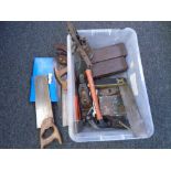 A crate containing vintage saws and tools, blow lamp, woodworking plane.