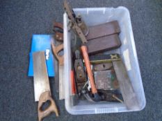 A crate containing vintage saws and tools, blow lamp, woodworking plane.