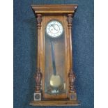 A Victorian walnut cased wall clock with pendulum and two weights.