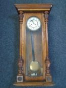 A Victorian walnut cased wall clock with pendulum and two weights.