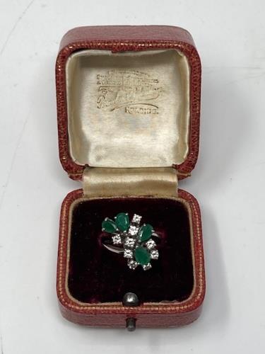 An 18ct white gold diamond and emerald ring, the floral design with nine diamonds,