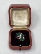 An 18ct white gold diamond and emerald ring, the floral design with nine diamonds,