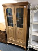 A 20th century oak double door cabinet with stained leaded glass doors, fitted with drawers beneath.
