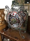 A 19th century wrought iron fire screen with a stained leaded glass panel.