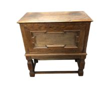 An early 20th century oak fall fronted cabinet on raised legs,