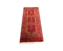 An Afghan long rug of geometric design on red ground,