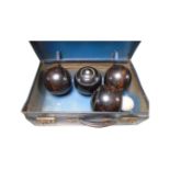 A vintage case containing four wooden lawn bowls