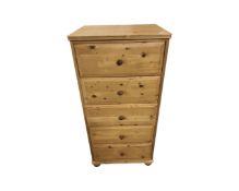 A contemporary narrow pine five drawer chest on bun feet,