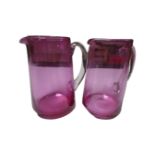 A pair of cranberry glass water jugs.
