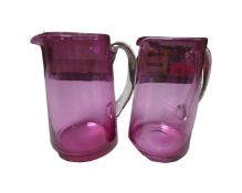 A pair of cranberry glass water jugs.