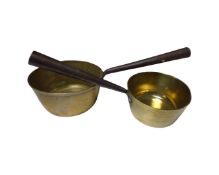Two antique brass sauce pans with cast iron handles.