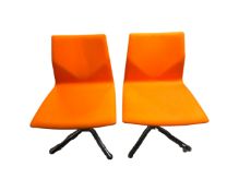 A pair of Danish swivel chairs upholstered in orange fabric on chrome bases