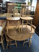 A drop leaf kitchen table in a teak finish together with a set of four beech dining chairs