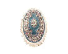 A Chinese embossed oval fringed rug on light blue ground,