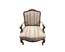 A carved walnut framed salon armchair in striped fabric