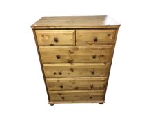A contemporary pine six drawer chest on bun feet,