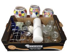 A box containing storage containers, a bottle rack, a white ceramic vase on stand, lampshades,