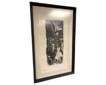 A limited edition monochrome print depicting figures in a street, 32cm by 59cm.