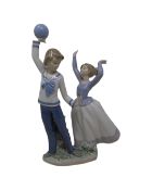 A Lladro figure of children playing with a ball.