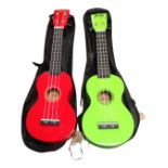 Two modern four-string ukuleles, one green and one red, both in black carry cases.