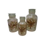 Three antique style glass storage jars with painted decoration.