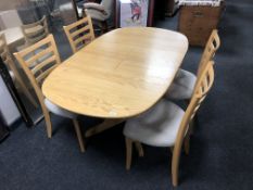 A contemporary Ercol light elm extending dining room table together with four chairs upholstered in