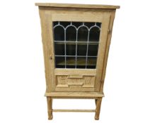A continental blond oak cabinet on stand with stained leaded glass door.