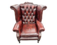 A Chesterfield ox blood button leather wingback armchair.