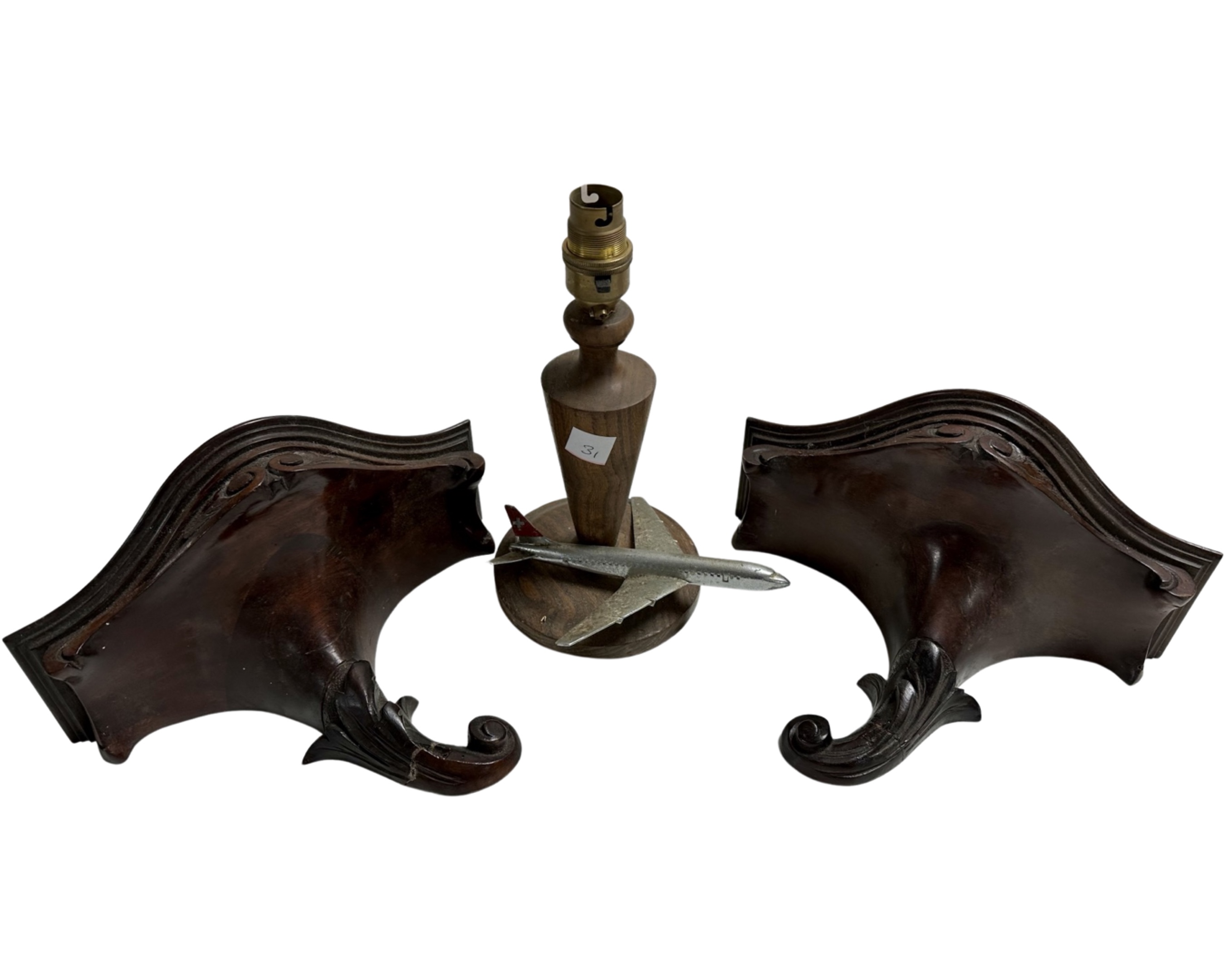 A pair of carved wooden wall brackets together with a table lamp surmounted by an aeroplane.