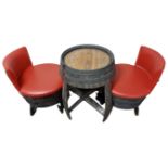 A barrel table together with a pair of wood and red vinyl chairs.