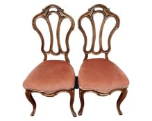 A pair of late 19th century carved walnut salon chairs in pink dralon upholstery.