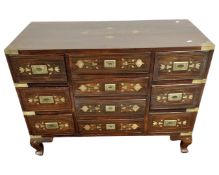 A hardwood low chest fitted with ten drawers, brass inlay and brass drop handles.