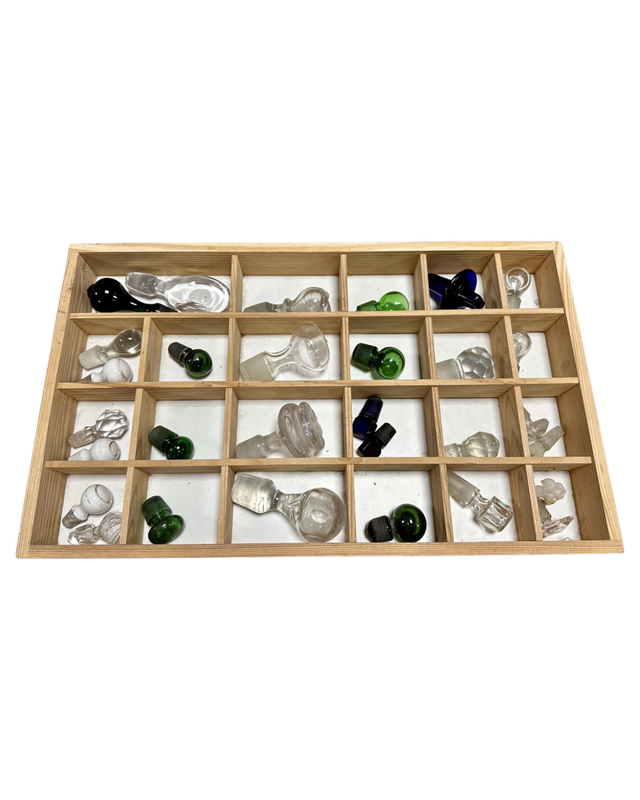 A pine drawer containing a quantity of glass decanter stoppers.