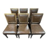 A set of six carved oak dining chairs in studded vinyl upholstery.