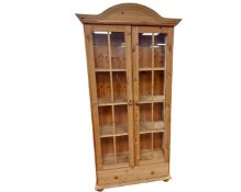 A pine glazed double door bookcase.