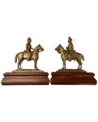 A pair of wooden and brass door stops in the forms of soldiers on horse back,