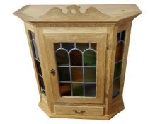 A Continental blond oak wall cabinet with stained leaded glass panels.