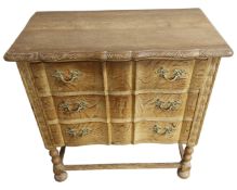 A blond oak serpentine front chest of three drawers.