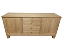 A contemporary light oak sideboard fitted with cupboards and drawers beneath.