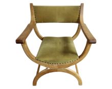 A Continental blond oak X-framed armchair in stud upholstery.